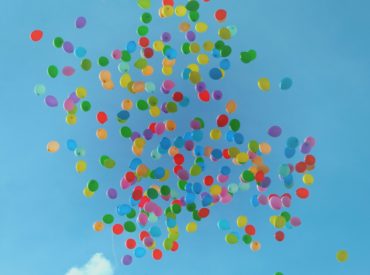 A bunch of balloons floating in the sky